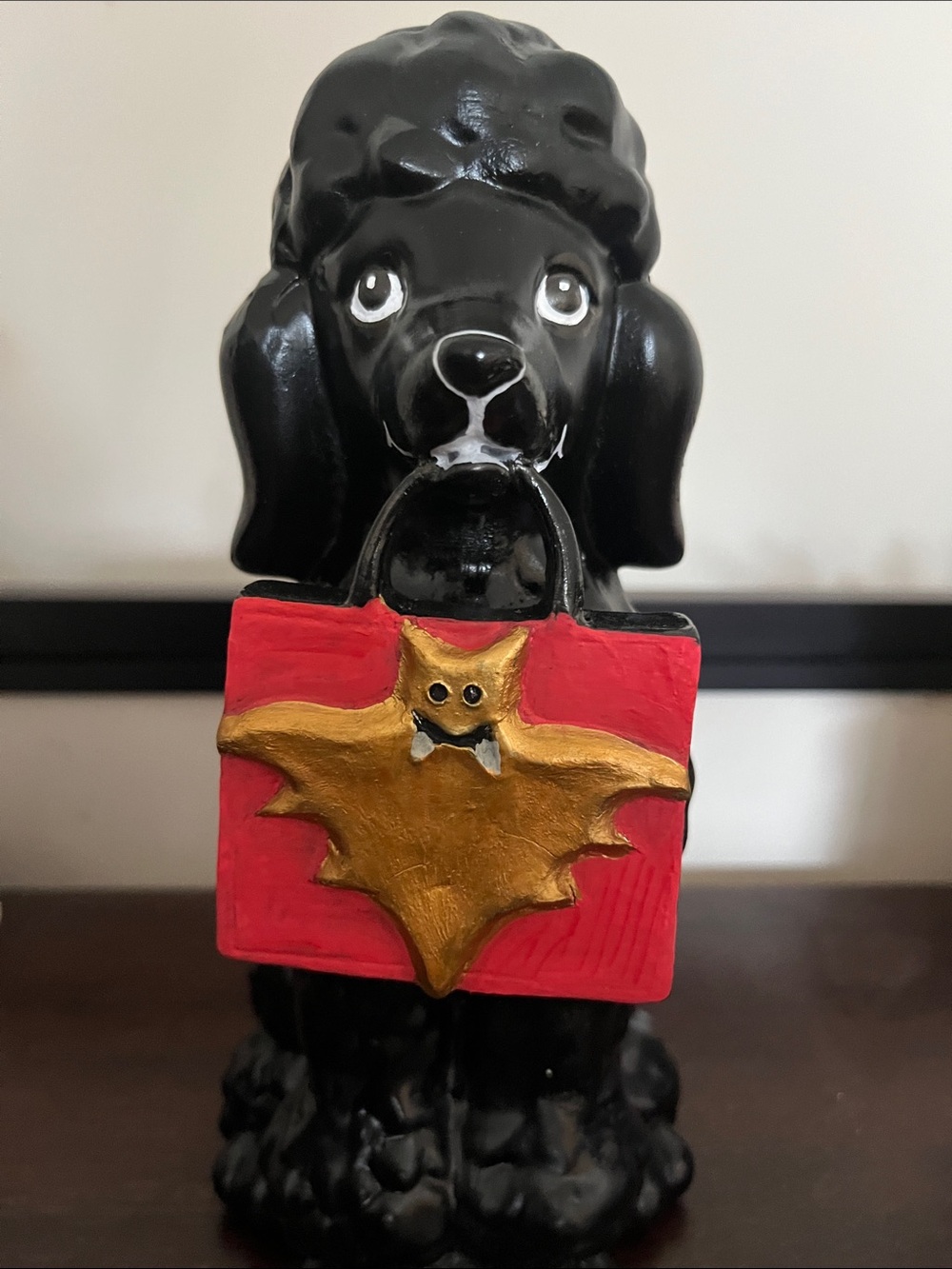 Black Poodle Holding Red Bag with Gold Bat Accent - Decorative Pet Statue